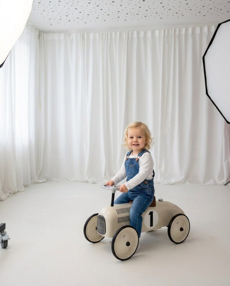 Kinderfotoshooting Trier – Weißes Studio, Kind mit Jeans Latzhose auf Retro-Rutschauto